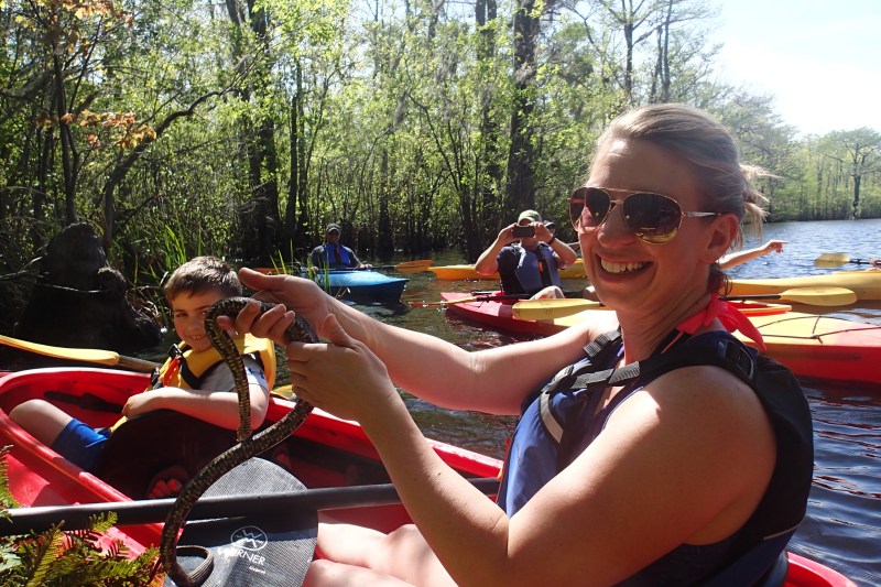 Kayakers on river holding snake